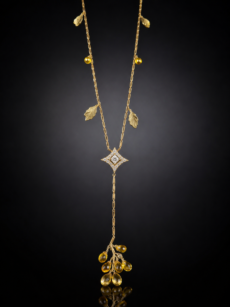 Yellow gold Y-necklace with leaf charms, a princess-cut diamond centerpiece and faceted yellow drops against a black background